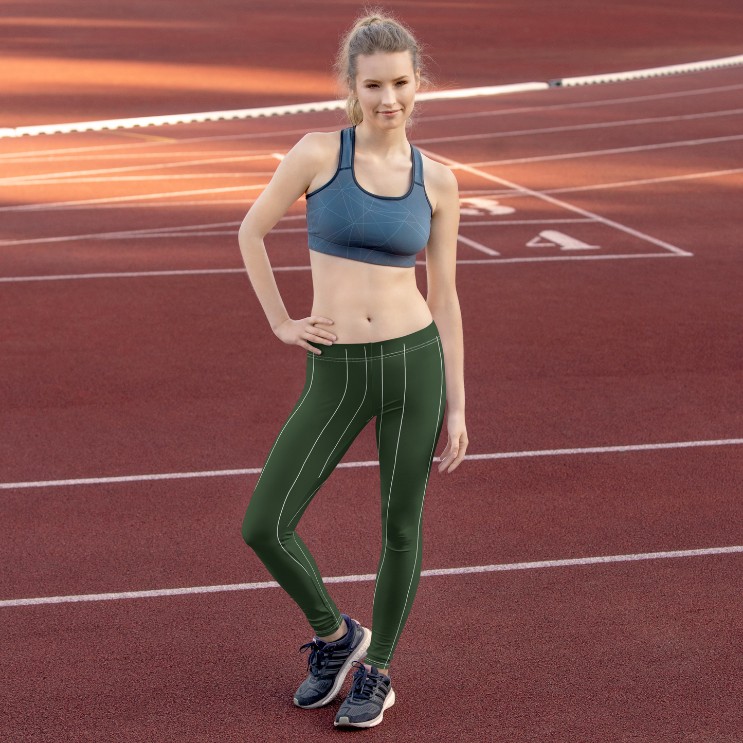 Woman in athletic wear and leggings standing on a running track