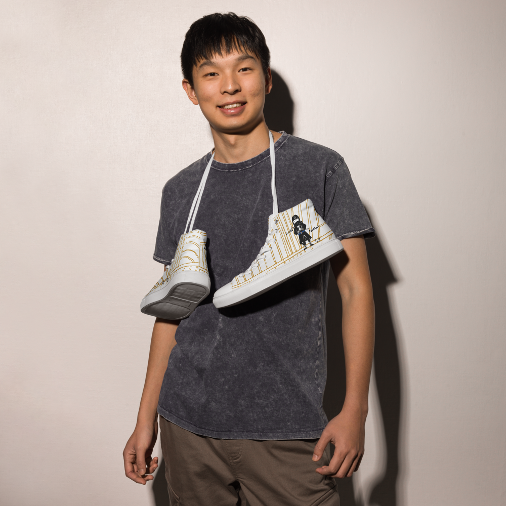 Person holding a pair of white yellow stripe high-top sneakers with a playful ninja graphic design and white laces, featuring a text 'Last ninja' on a plain background